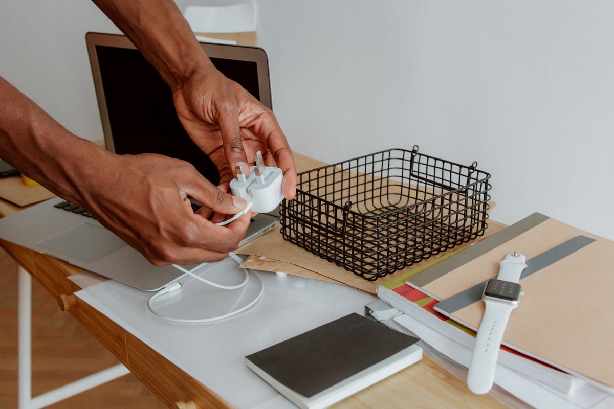 A person organizing a charger and accessories above a work desk