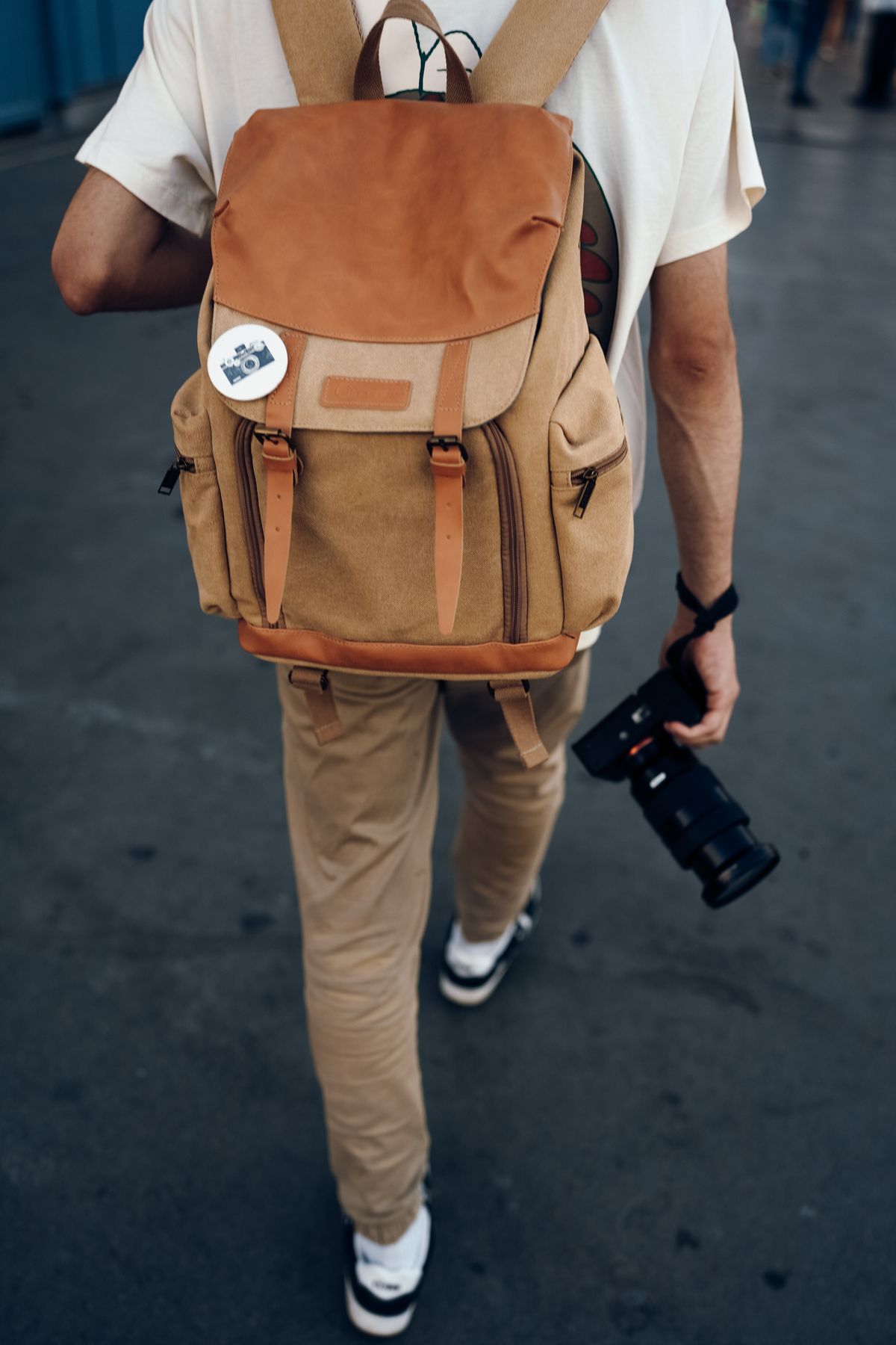 A traveler with a backpack carrying a camera outdoors