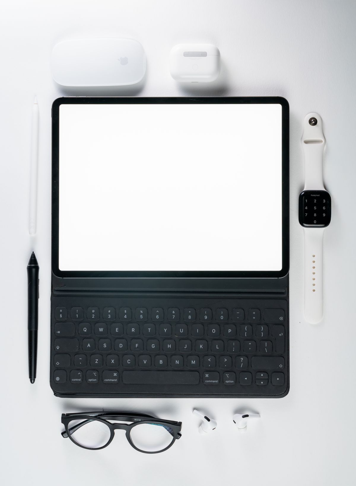 A tablet, compact keyboard and everyday accessories arranged together