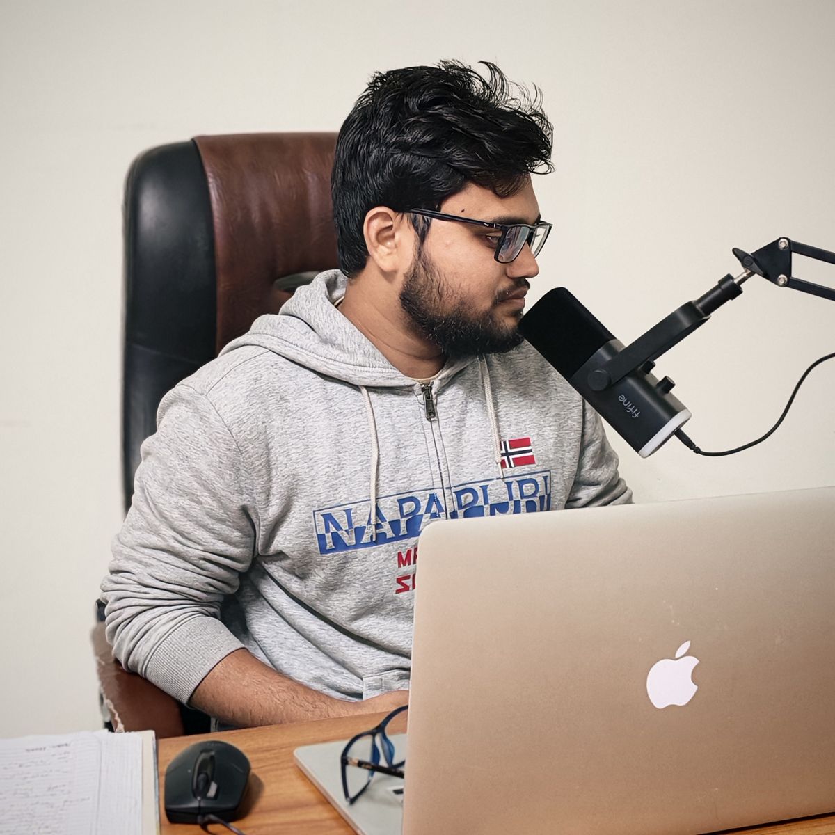 A person speaking into a microphone at a laptop in a home office