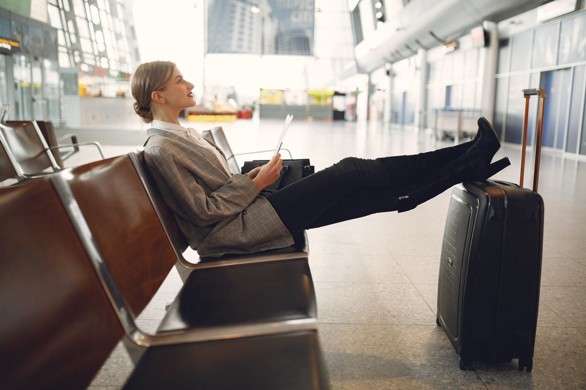 A traveler using a tablet while seated with luggage in an airport