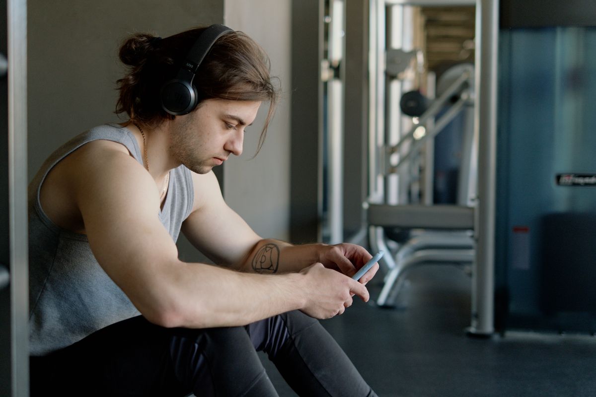 A man using a smartphone while wearing headphones at the gym