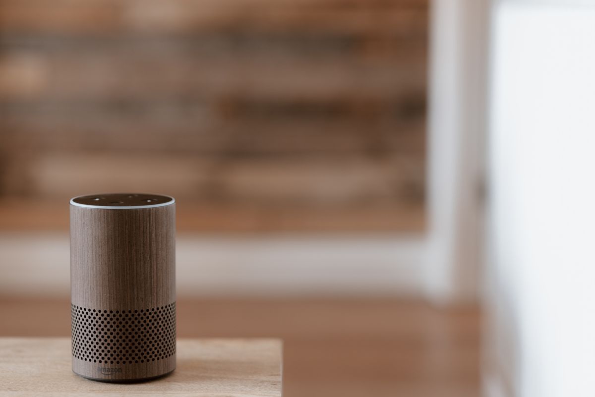 A compact smart speaker on a wooden surface in a home
