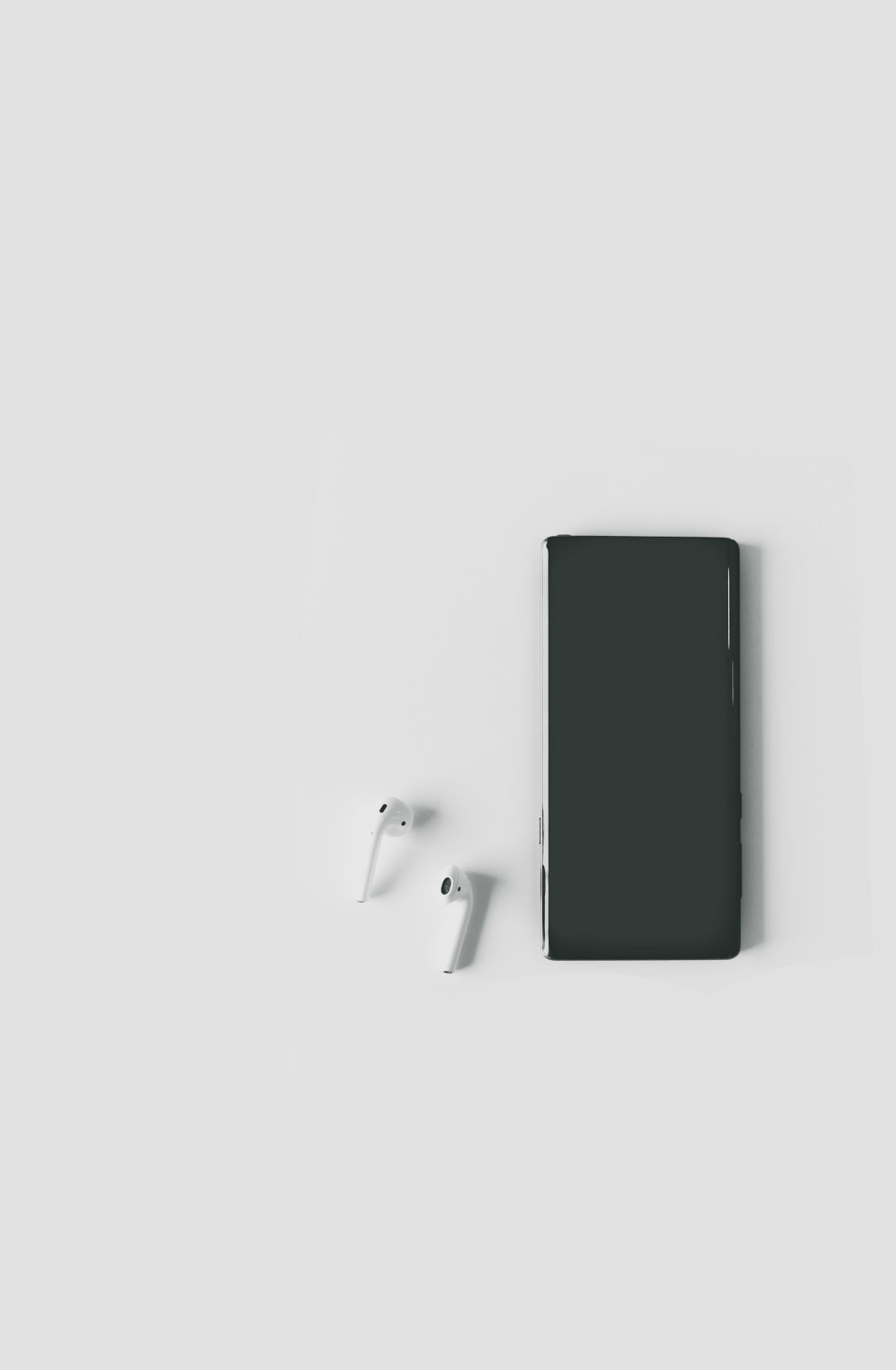 A smartphone and wireless earbuds placed together on a light surface