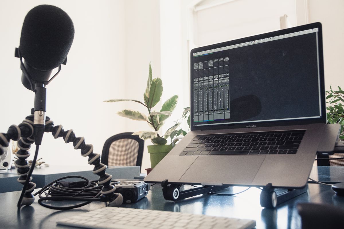 A laptop and microphone together on an audio work desk