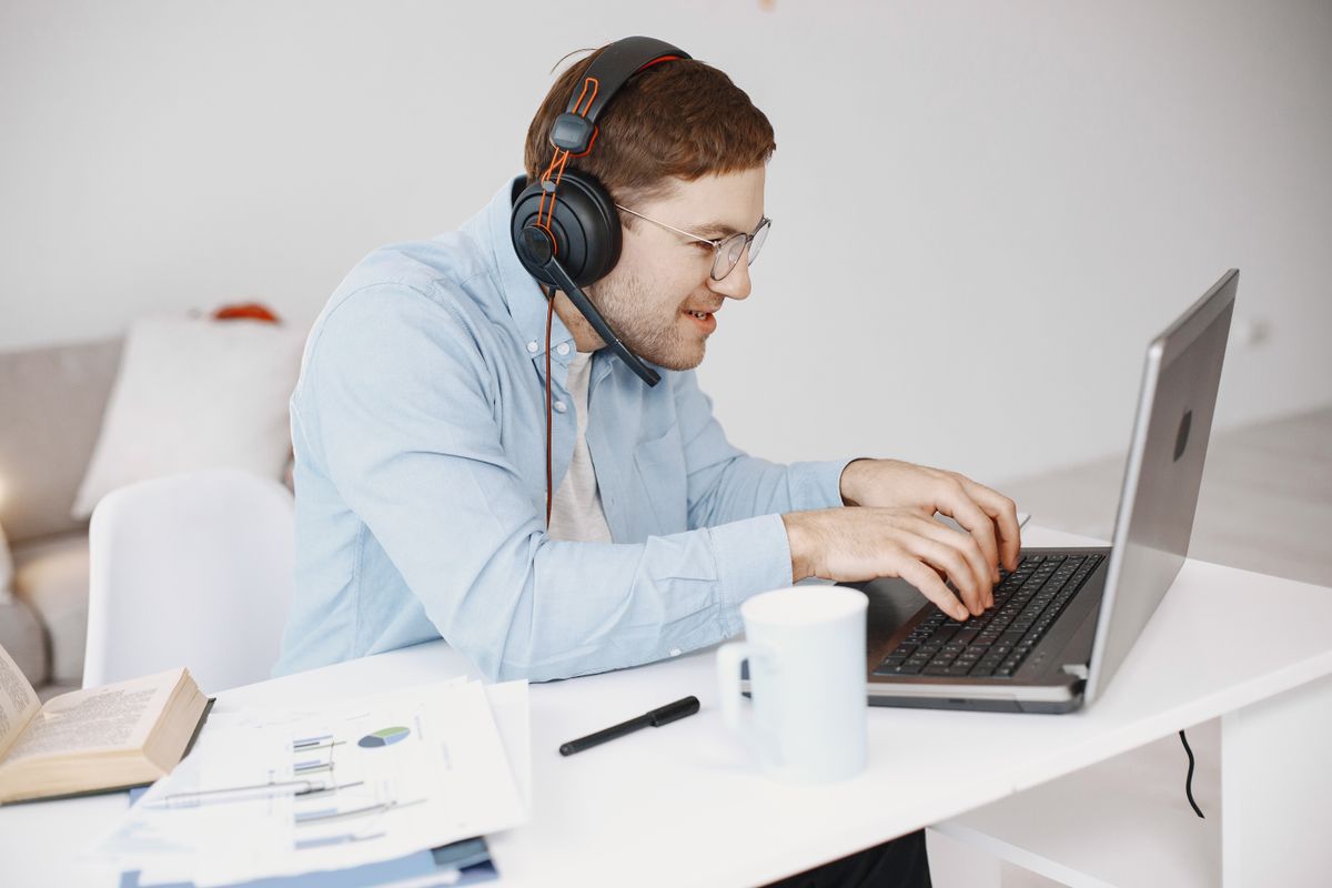 A person wearing headphones while working at a laptop at home
