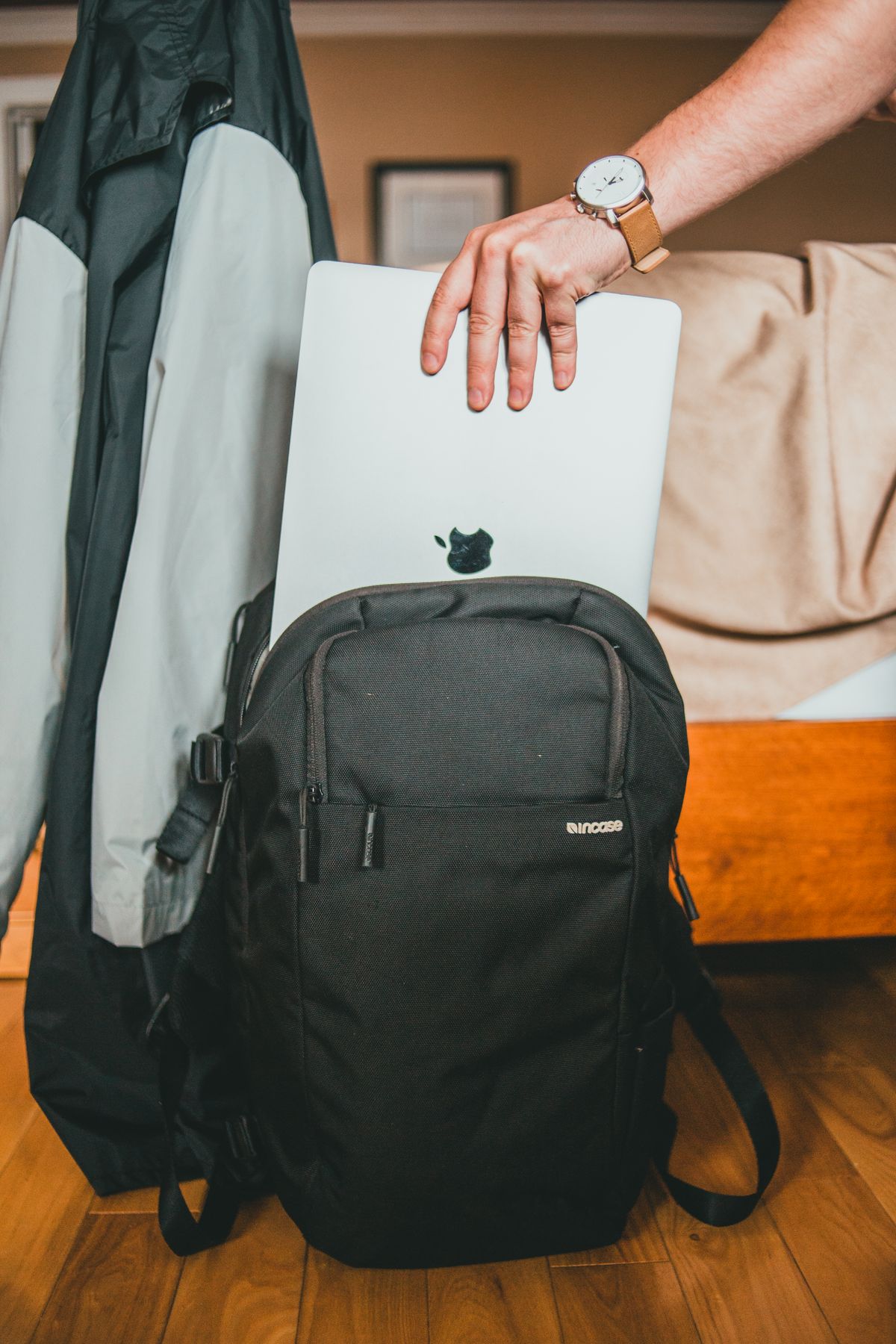 A person placing a laptop into a backpack at home